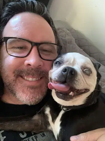 Cheek-to-cheek selfie of Raymond with a white-and-black bulldog-type dog, Long Beach dog walker